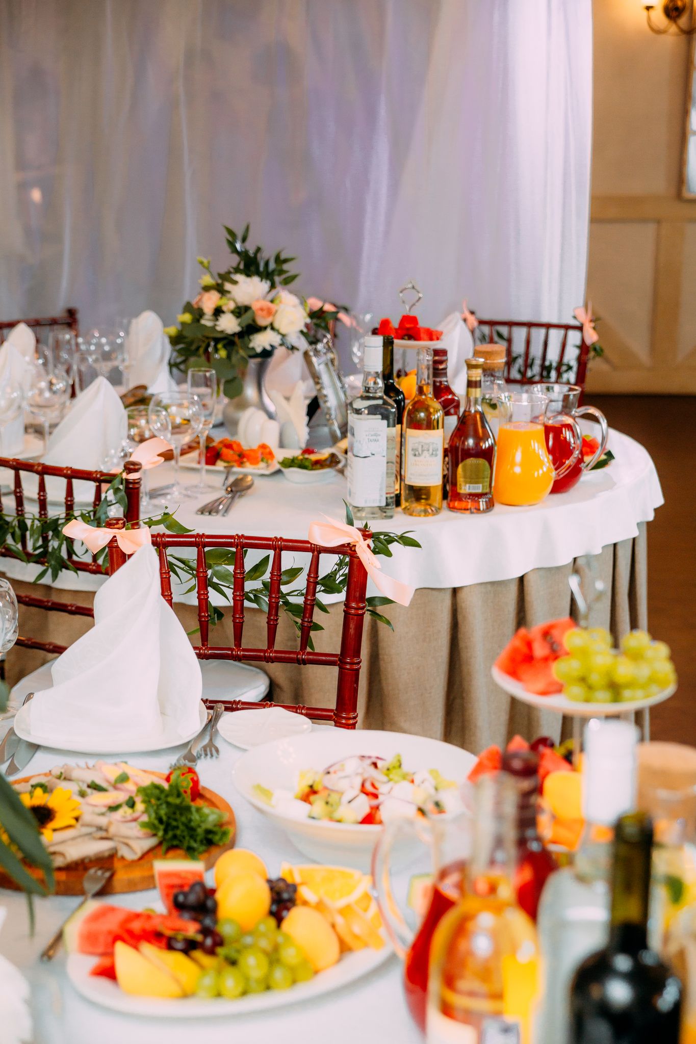 Tables decorated with fresh flowers with fruits and bottle of drinks in restaurant for occasion